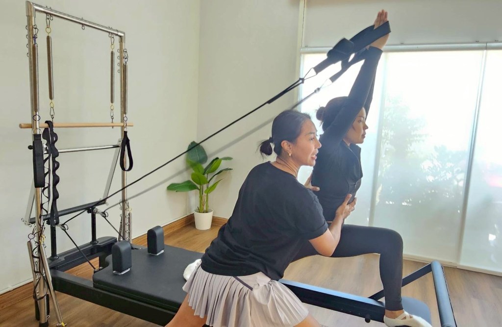Standing lunge with straps on the reformer tower